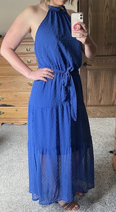 A reviewer modeling a blue, floor-length halter dress.