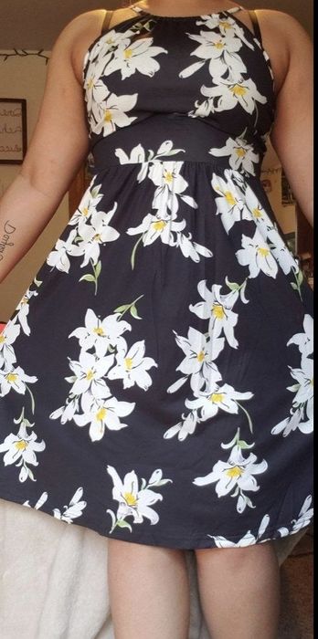 A reviewer dressed in a knee-length floral print dress.