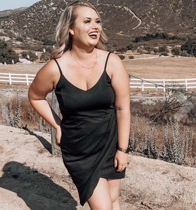 A reviewer showcasing a mini black slip dress.