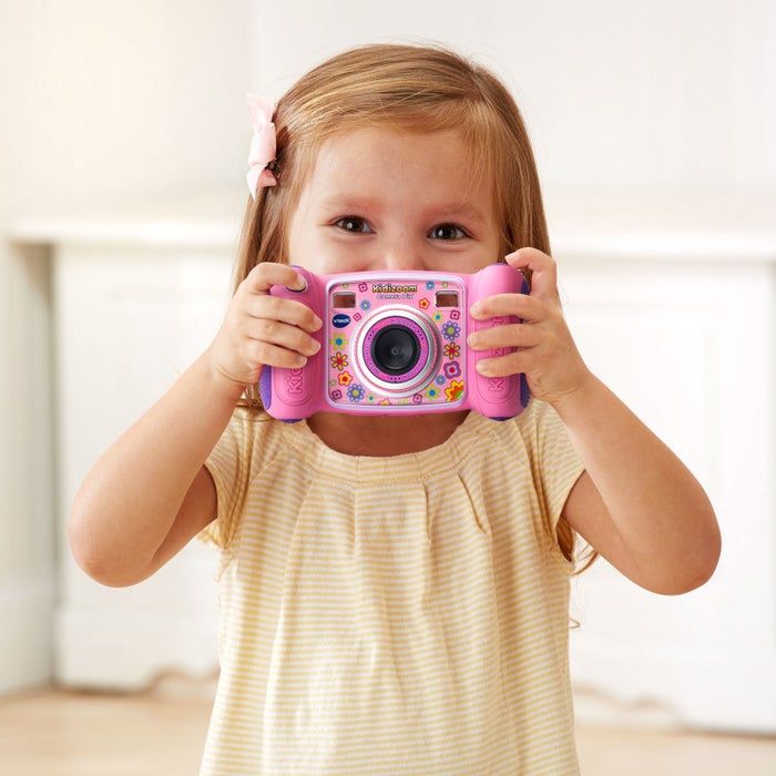 A child holding a pink VTech Kidizoom camera with a charming floral design