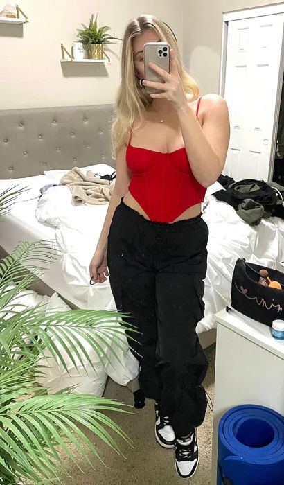 A reviewer dressed in black pants complemented by a striking red corset top.