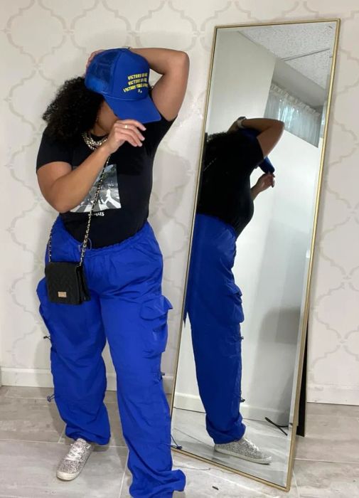 A reviewer sporting blue trousers paired with a fitted black T-shirt tucked neatly inside.