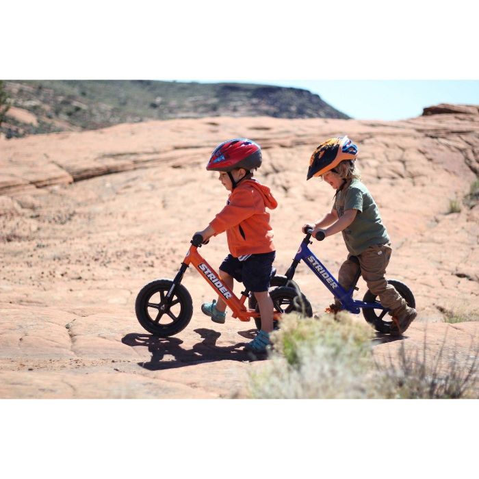 Two kids riding balance bikes outdoors