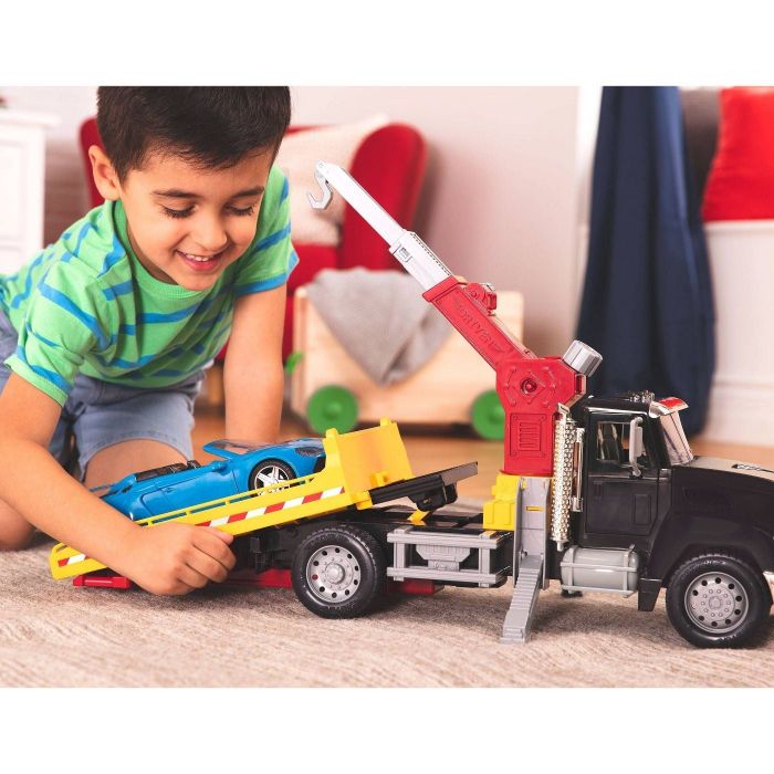 A child playing with a crane truck and a car.