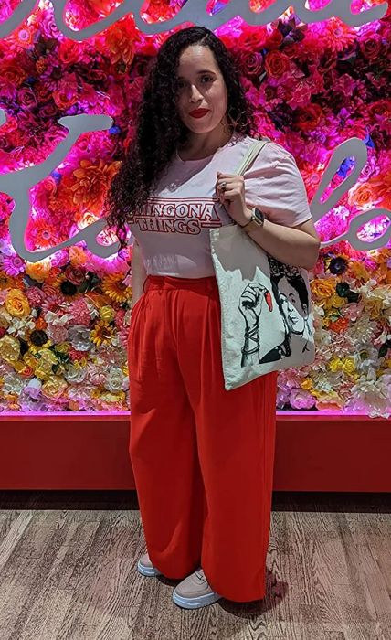 A reviewer sporting the orange wide-leg pants paired with a tucked-in white T-shirt.