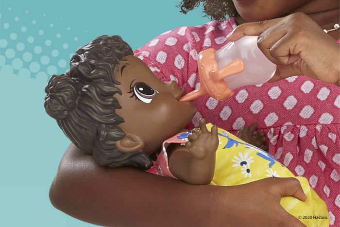A baby doll sipping from a bottle, dressed in a vibrant outfit.