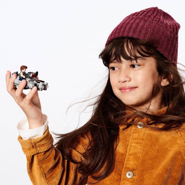 A young girl holding a Star Wars Lego ship.
