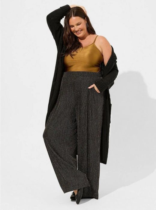 A model is styled in the pants with a tucked-in camisole, showcasing a chic and polished look.