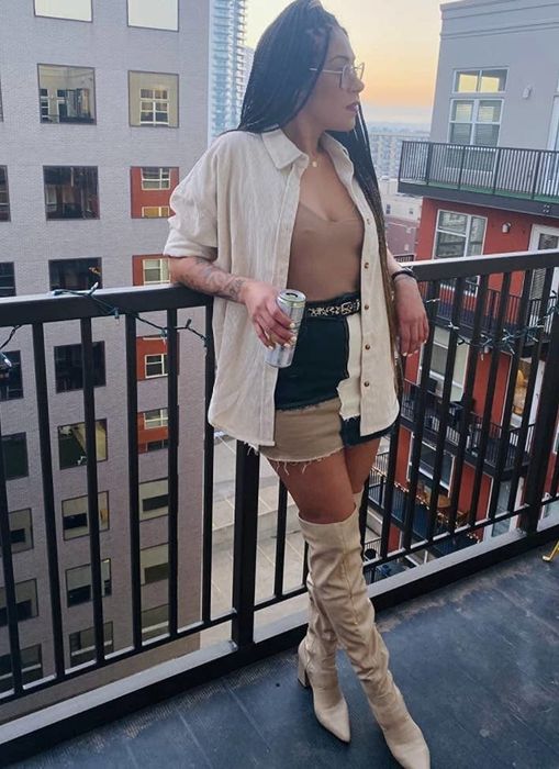 A reviewer sporting a sheer top with a tank, denim skirt, and over-the-knee boots.