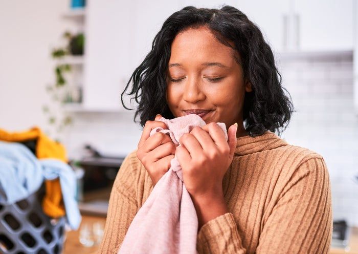 A person holding a freshly-washed shirt to their face, inhaling the clean, fresh scent of laundry.