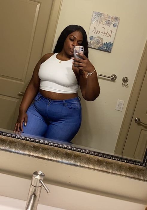 Another reviewer capturing a mirror selfie in a white tank top.