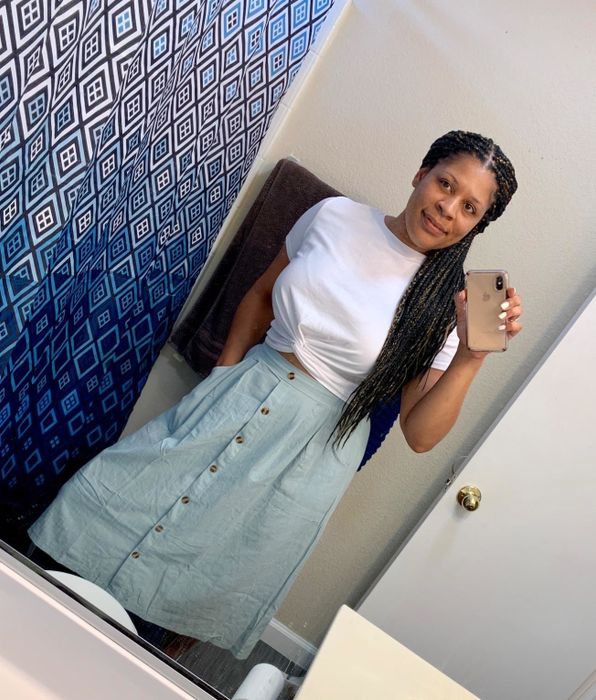 reviewer taking a mirror selfie while wearing the tee with a button-up midi skirt