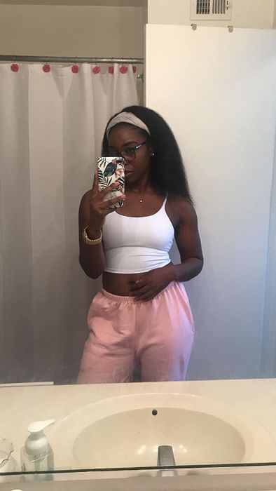 reviewer posing in front of a bathroom mirror wearing a white tank top