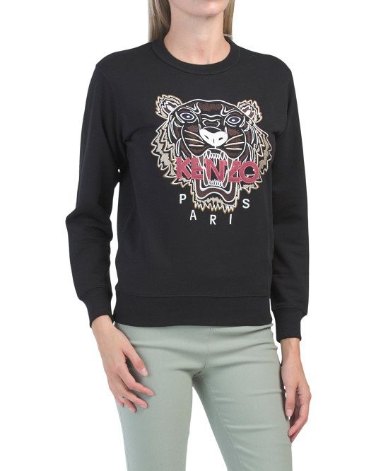A model is wearing a sweatshirt with the Kenzo tiger embroidered on the front.