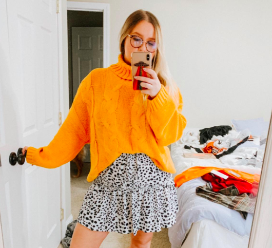 A customer photo of them rocking the sweater in a vibrant orange shade.