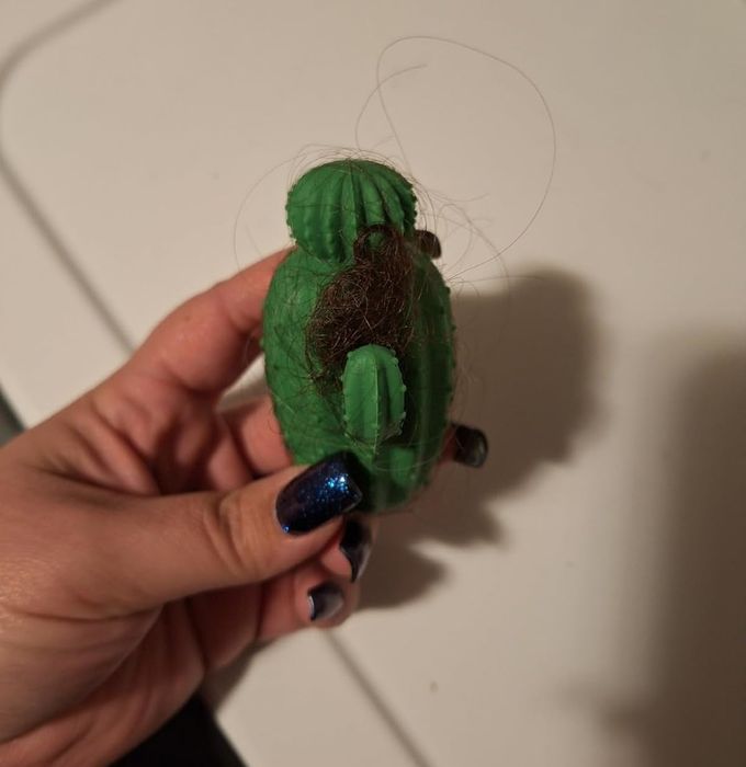 The reviewer is shown holding the dryer ball, with hair attached to it.