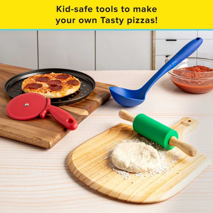 Pizza pan next to a red pizza cutter, green rolling pin on a serving board with dough, blue ladle beside a bowl of sauce