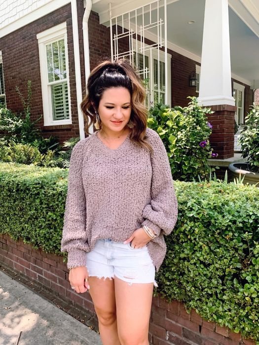 A customer review photo of them wearing the sweater in light purple.