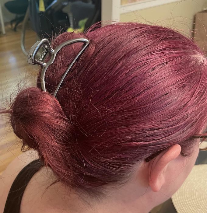 The reviewer styling their hair with the silver clip.
