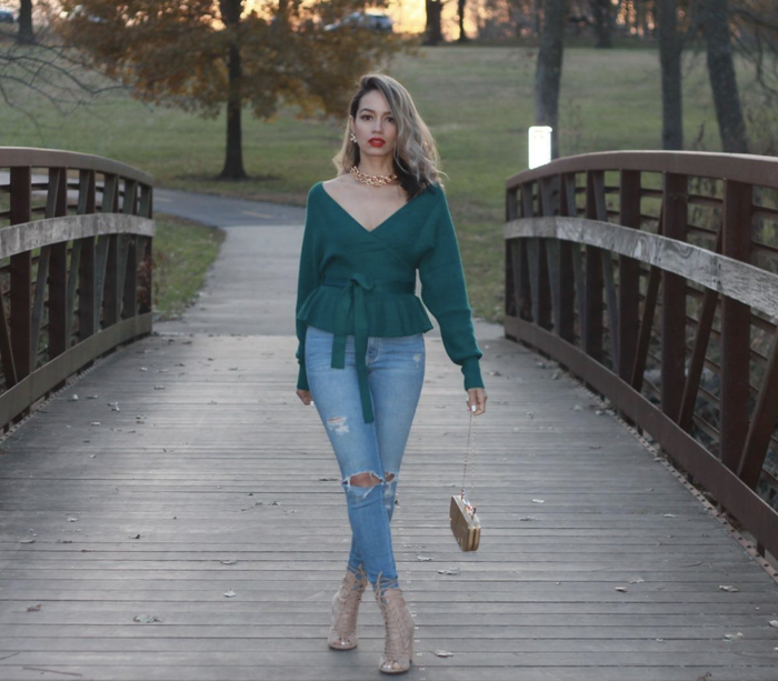 A customer photo of them wearing the sweater in a vibrant green, standing on a bridge.