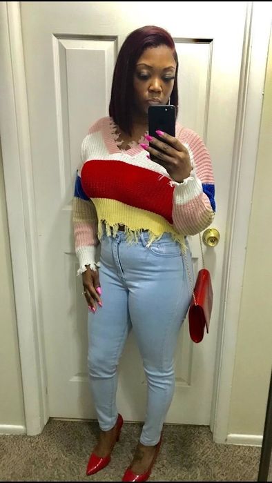 A customer review photo of them in the sweater featuring stripes in pink, white, red, and yellow.
