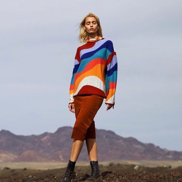 A model is seen wearing a sweater featuring blue and red swirling patterns.
