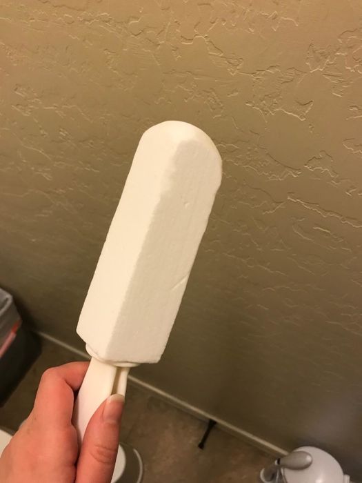 A white pumice stone with an attached handle for easy use.