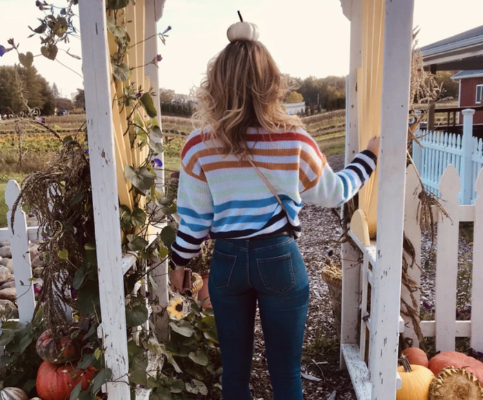 A customer photo of them wearing the sweater at a pumpkin patch, adding to the autumn vibes.