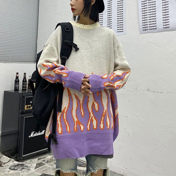 A model dons an oversized sweater adorned with purple flames along the hem and sleeves.