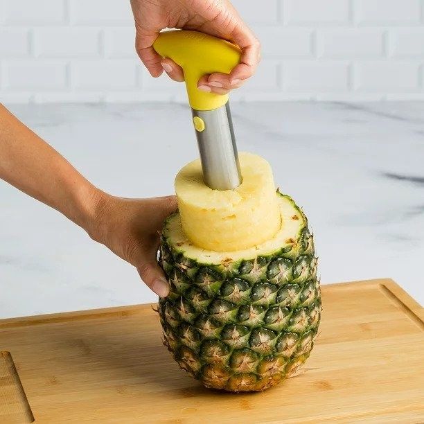 A person using a pineapple slicer to remove the pineapple from its skin