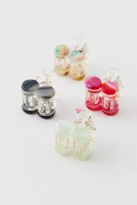 Four pairs of clip-on earrings that mimic pearls, each in a different shade, arranged neatly on a white surface.