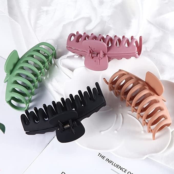 Four matte claw clips in shades of green, pink, black, and tan