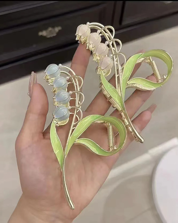 individual holding two lily-themed claw clips in their hand