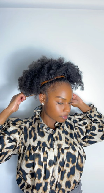 The identical model styling their hair into a voluminous puff.
