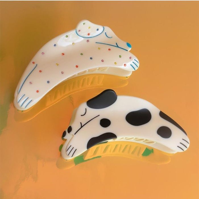 Two dog-themed hair claws, one adorned with tiny rainbow rhinestones and the other with bold black spots