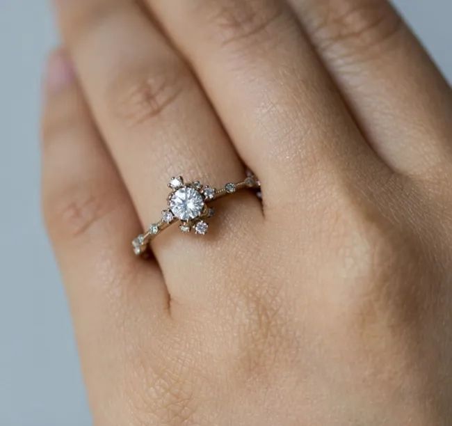 A diamond ring featuring four smaller diamonds surrounding a larger center stone, with more small diamonds running down the band.