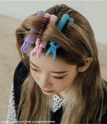 a model showcasing four volumizing curlers in their hair