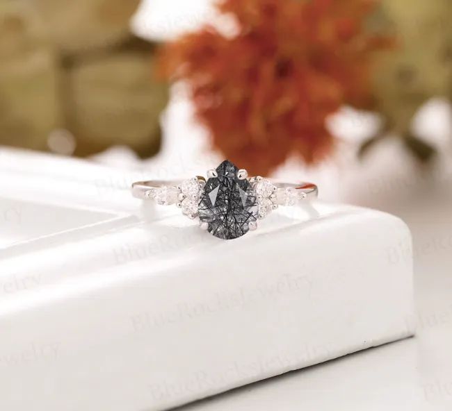 A pear-shaped black quartz ring adorned with diamonds subtly set along the silver band.