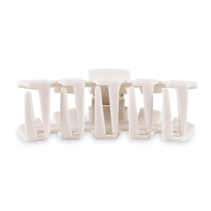 A close-up view of a white plastic hair claw clip with interlocking teeth, used to hold hair in place.