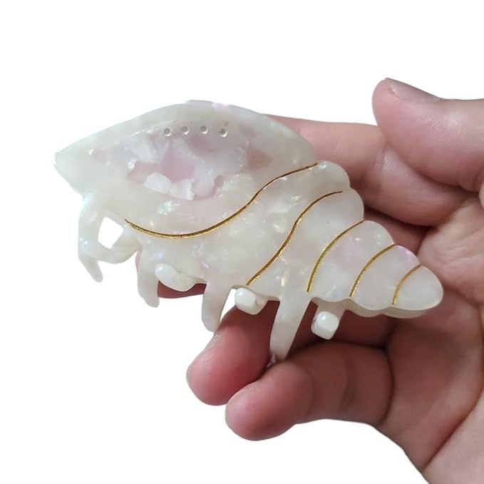 A hand holds a translucent hair claw with gold accents.