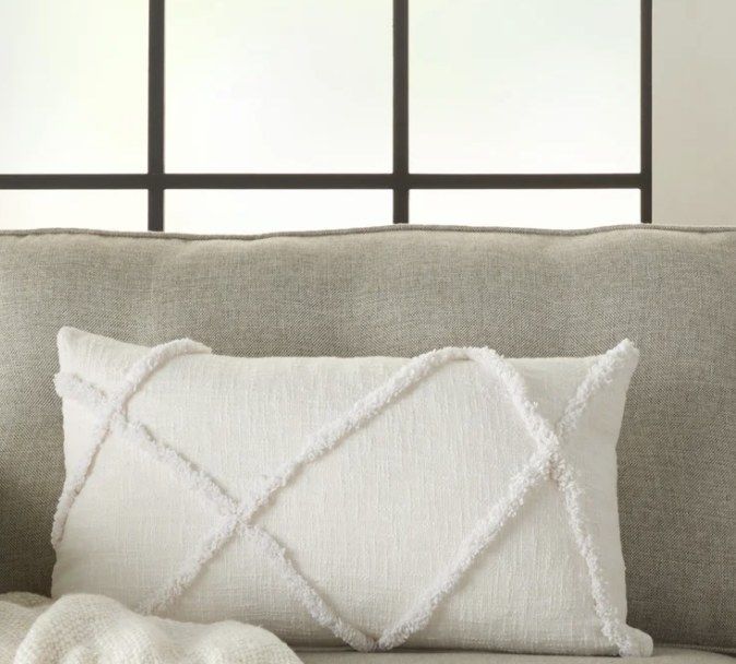 This pillow features a crisp white design with beautifully tufted criss-cross edges, adding a sophisticated touch to any decor.