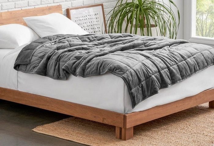 a gray weighted blanket elegantly draped over a bed