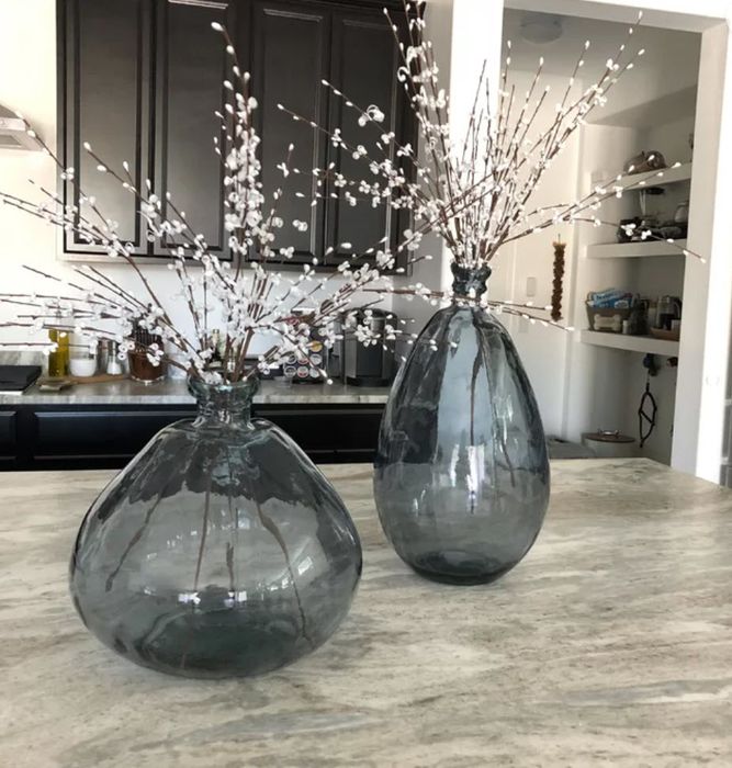 Two transparent glass vases, one wide and one tall, adorned with delicate cherry blossom branches