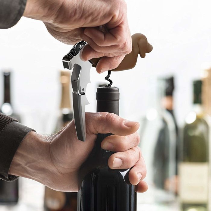 A model flipping the bottom of the dachshund corkscrew to reveal the tool they are using to open a bottle of wine