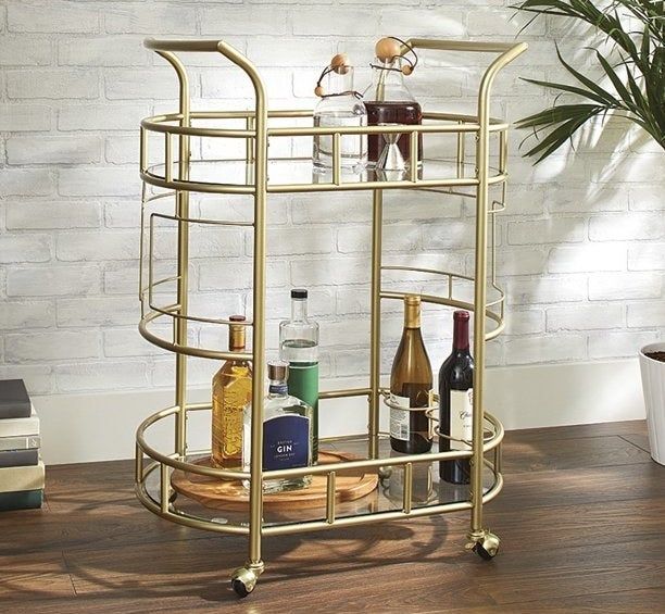 A gold bar cart adorned with drinks on it.