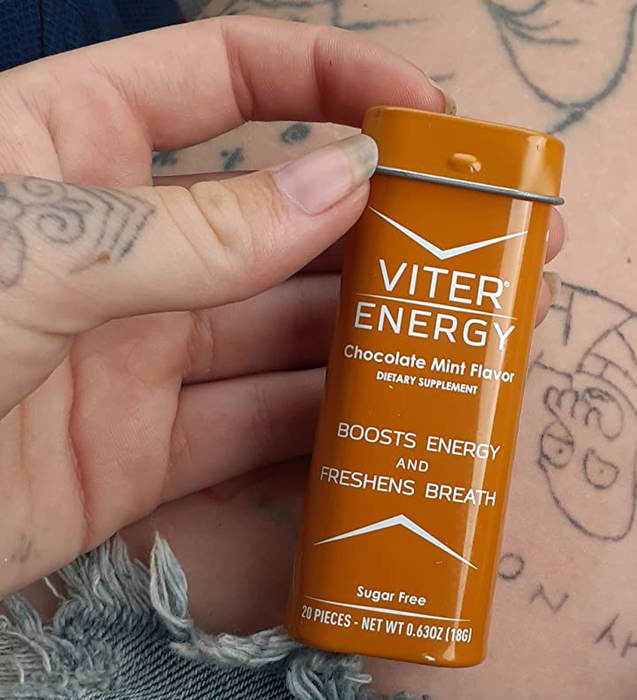 A reviewer holding a box of sugar-free caffeinated mints, perfect for an on-the-go energy pick-me-up.