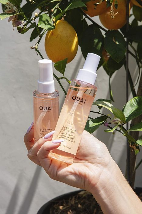 A hand is shown holding two bottles of Ouai hydrator.