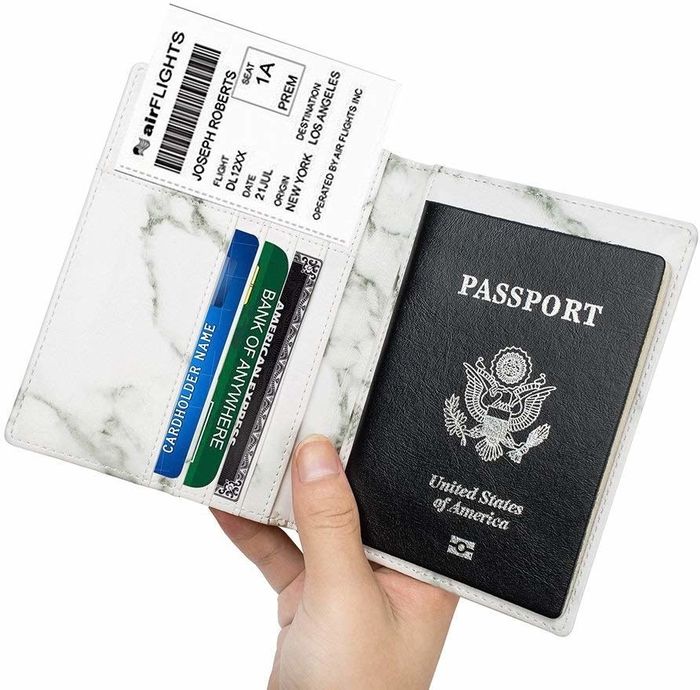 The open passport holder displaying a passport, boarding pass, and three credit cards tucked inside