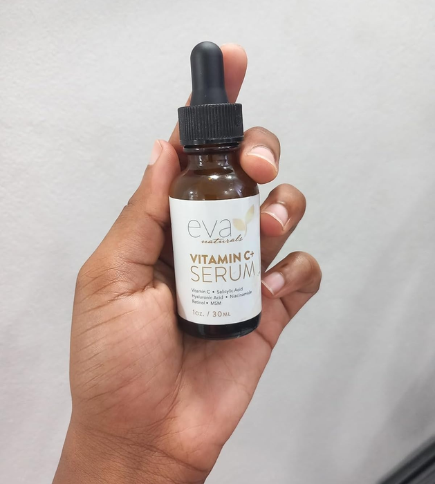 Hand holding a bottle of Eva Naturals Vitamin C+ Serum with a dropper cap ready to apply