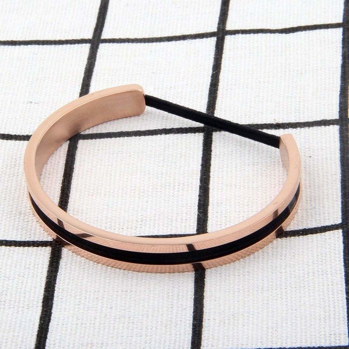 A gold bracelet featuring a groove to hold a hair tie
